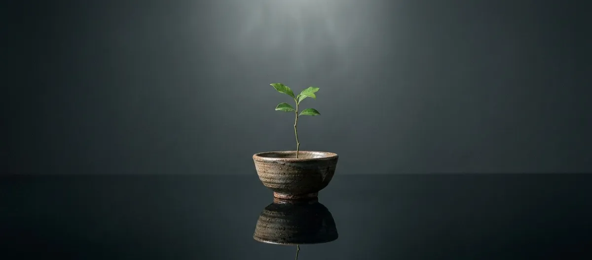 Fotografia conceitual de uma pequena planta refletida em um espelho d'água, simbolizando a construção delicada da própria identidade e o desenvolvimento do eu